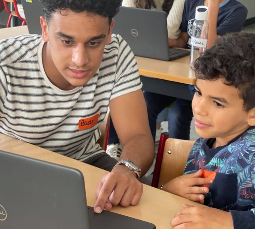 Een leraar helpt een jongetje bij programmeren