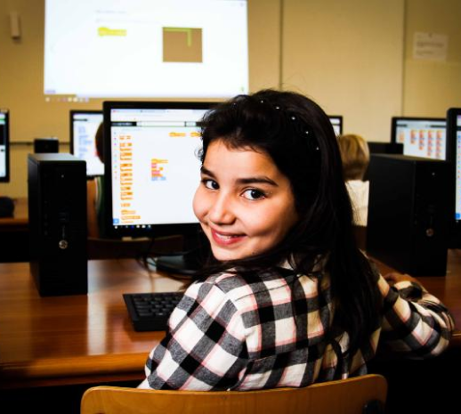 Een meisje lacht tijdens het programmeren met Scratch